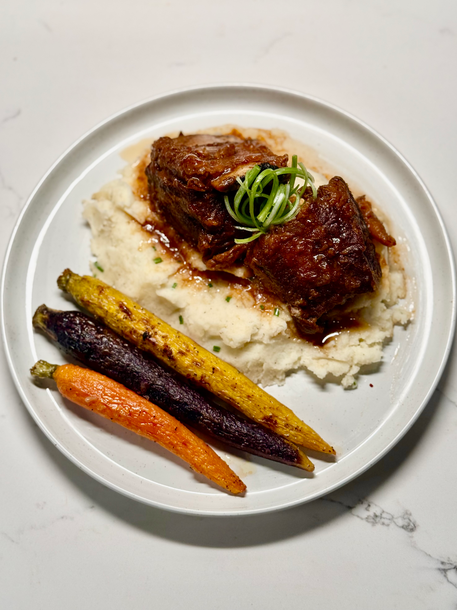 Overhead shot of braised miso ginger short ribs with mashed potatoes and carrots