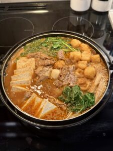 Homemade malatang with beef, bok choy, tofu, fish balls, mushrooms, and noodles in a nabe hot pot bowl