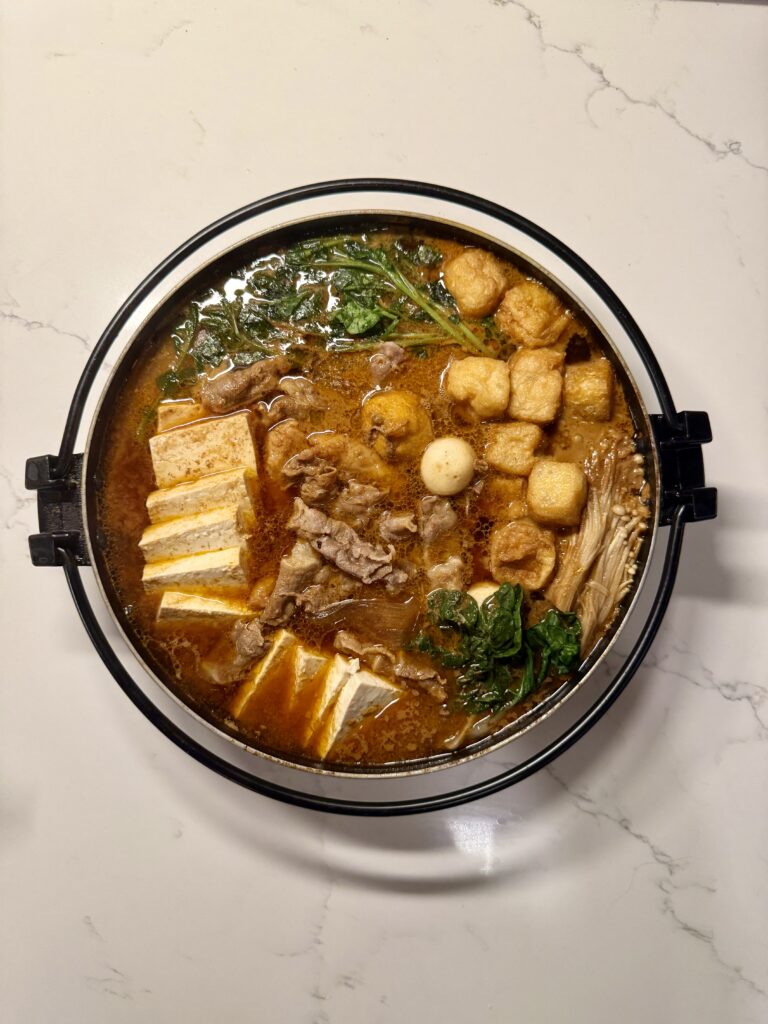 Homemade malatang with beef, bok choy, tofu, fish balls, mushrooms, and noodles in a nabe hot pot bowl