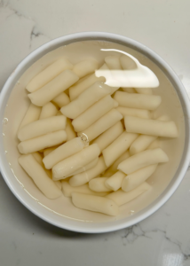 close up of bowl of soaked tteok (korean rice cakes)