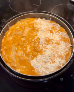 Close-up of rose tteokbokki in a skillet topped with melted mozzarella.