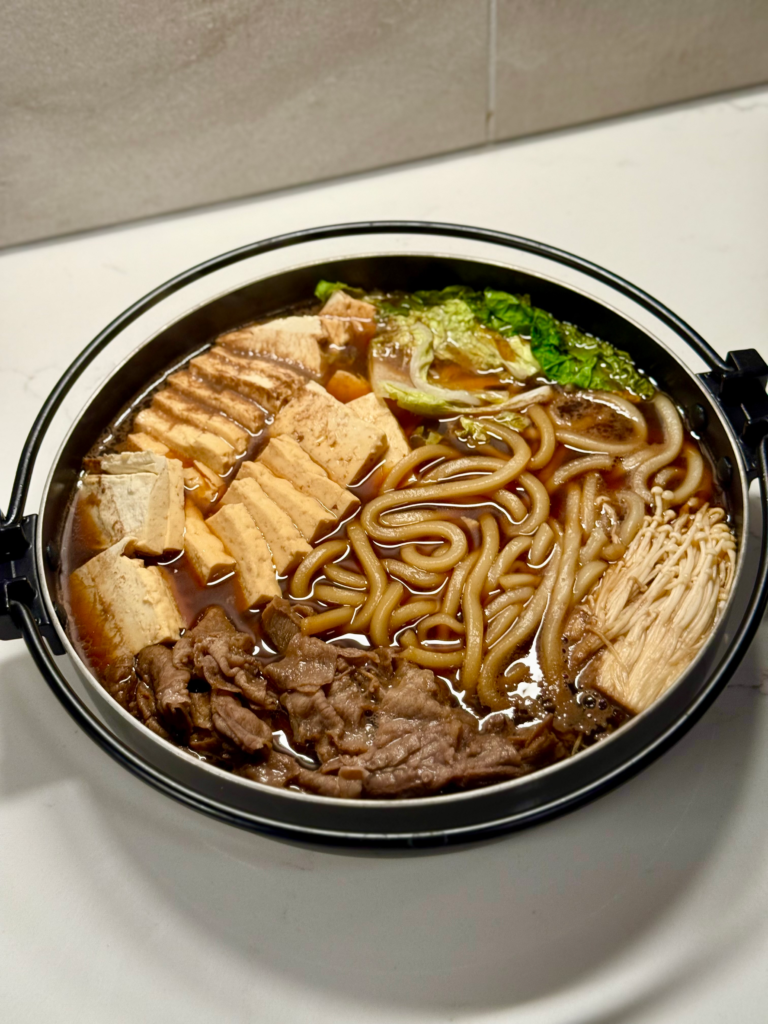 Close-up of sukiyaki hotpot served in a bowl with beef, mushrooms, and napa cabbage, showing the glossy warishita broth from this homemade sukiyaki recipe.