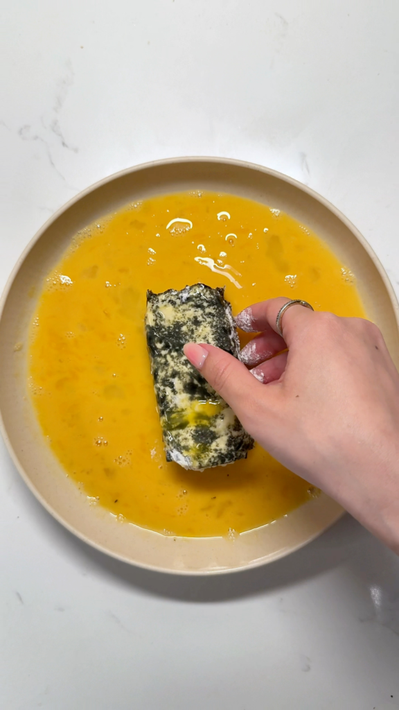 close-up shot of spam musubi being coated in egg