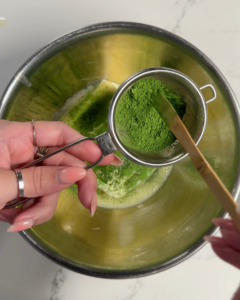 Sifting vibrant green matcha powder into the butter.