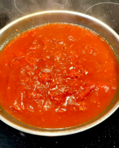 Tomato sauce simmering in a skillet, thick and glossy for spaghetti with burrata.
