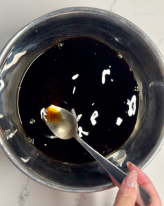 Mixing sukiyaki warishita sauce in a bowl with soy sauce, mirin, sake, and sugar before pouring into the hotpot for authentic Japanese flavor.