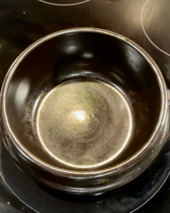 Korean stone pot preheating on stovetop before adding broth for mala soup dumplings