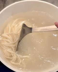 Thin wheat noodles boiling in a pot of water — first step in preparing traditional Chinese scallion oil noodles.